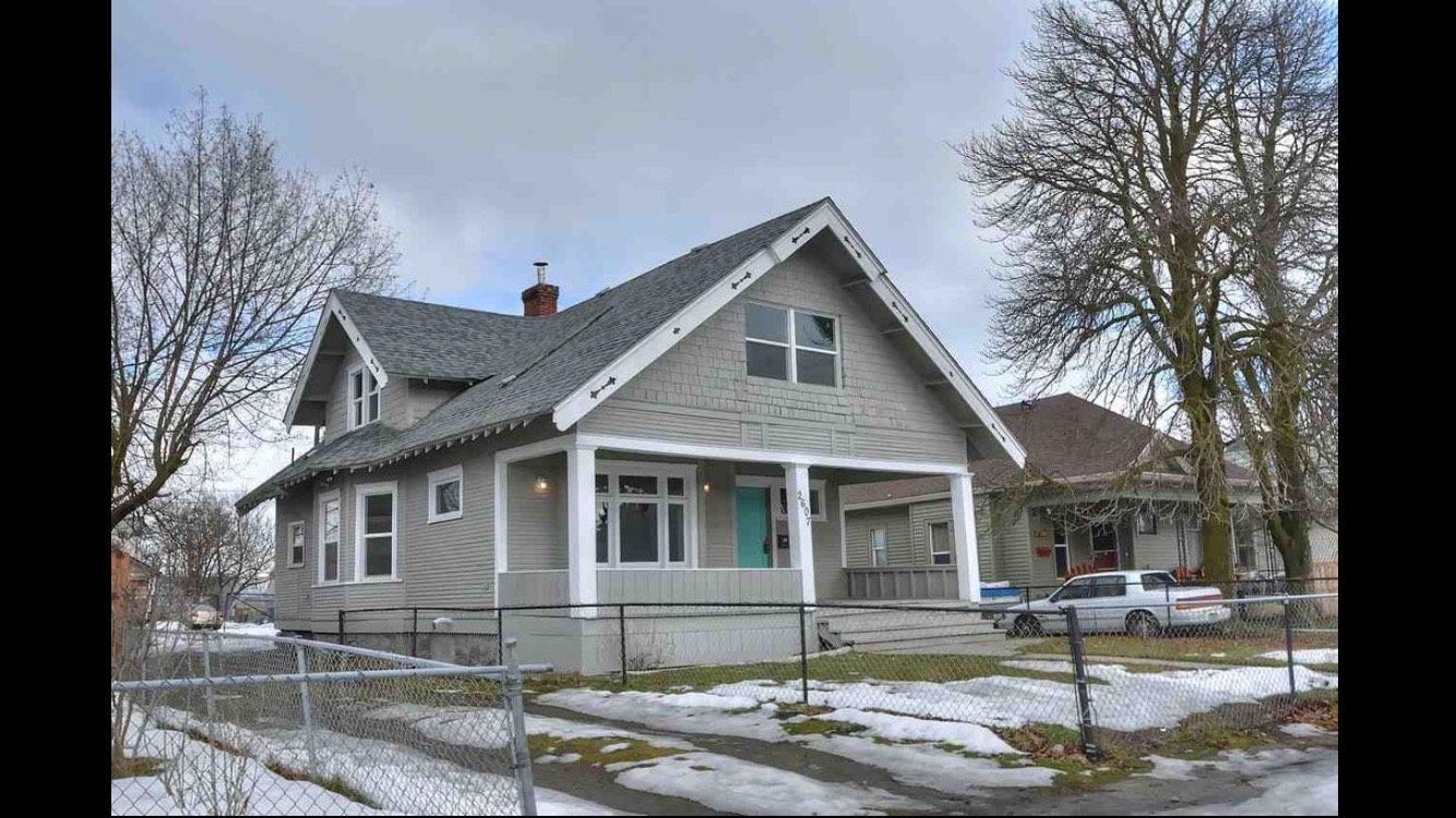 A house with a porch and a car parked in front of it