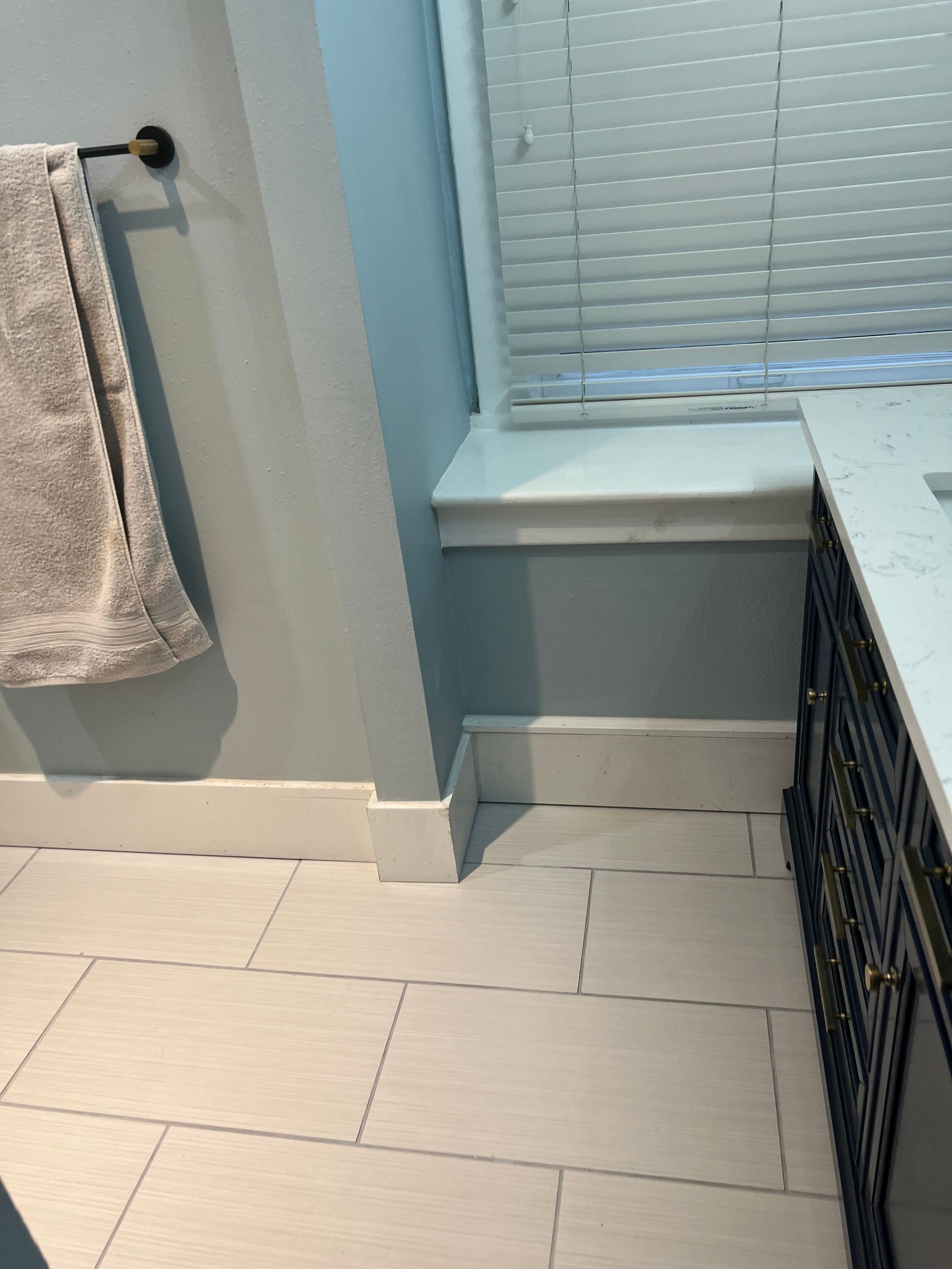 A towel is hanging on a towel rack in a bathroom next to a window.