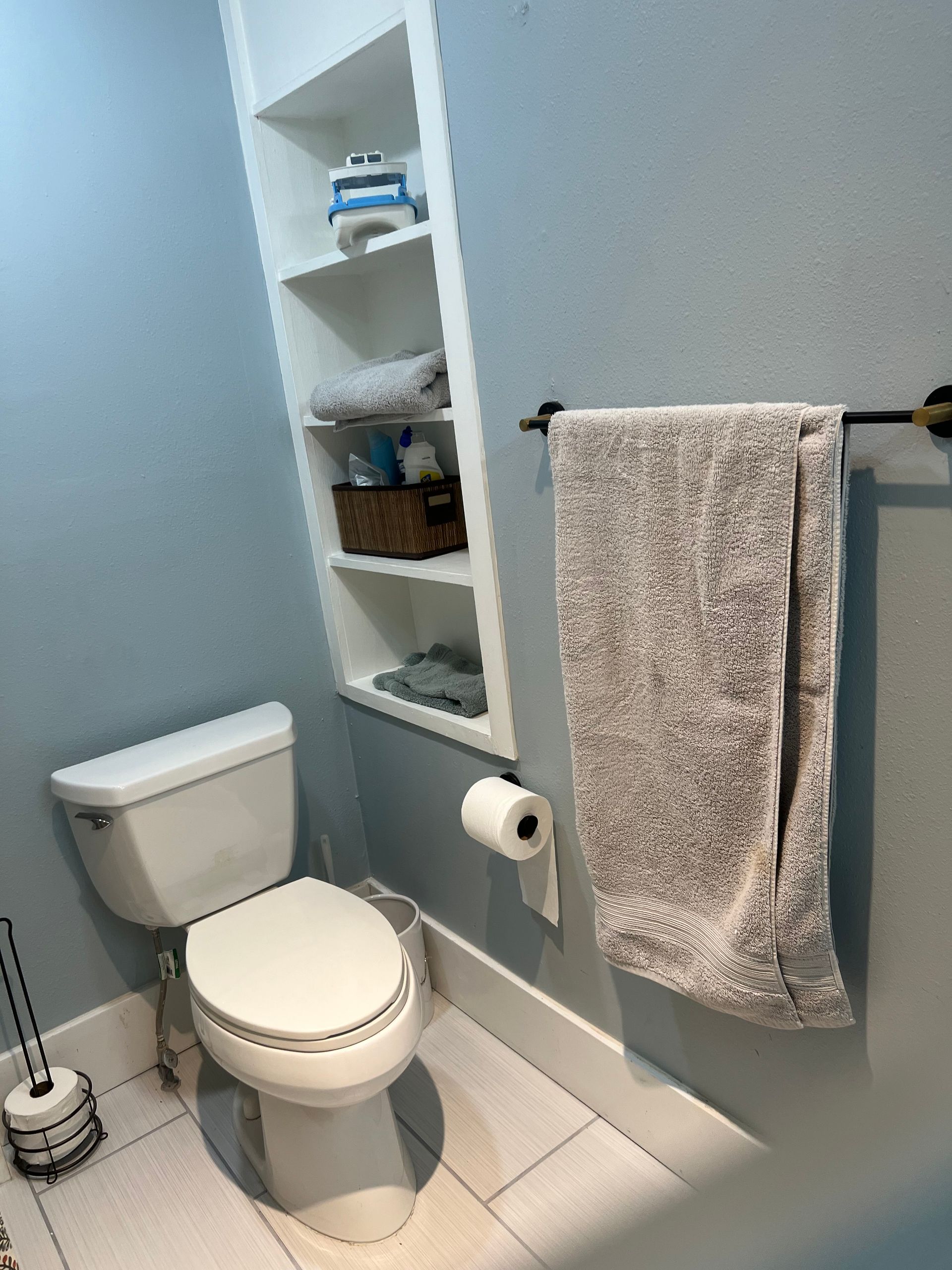 A bathroom with a toilet and a towel hanging on the wall