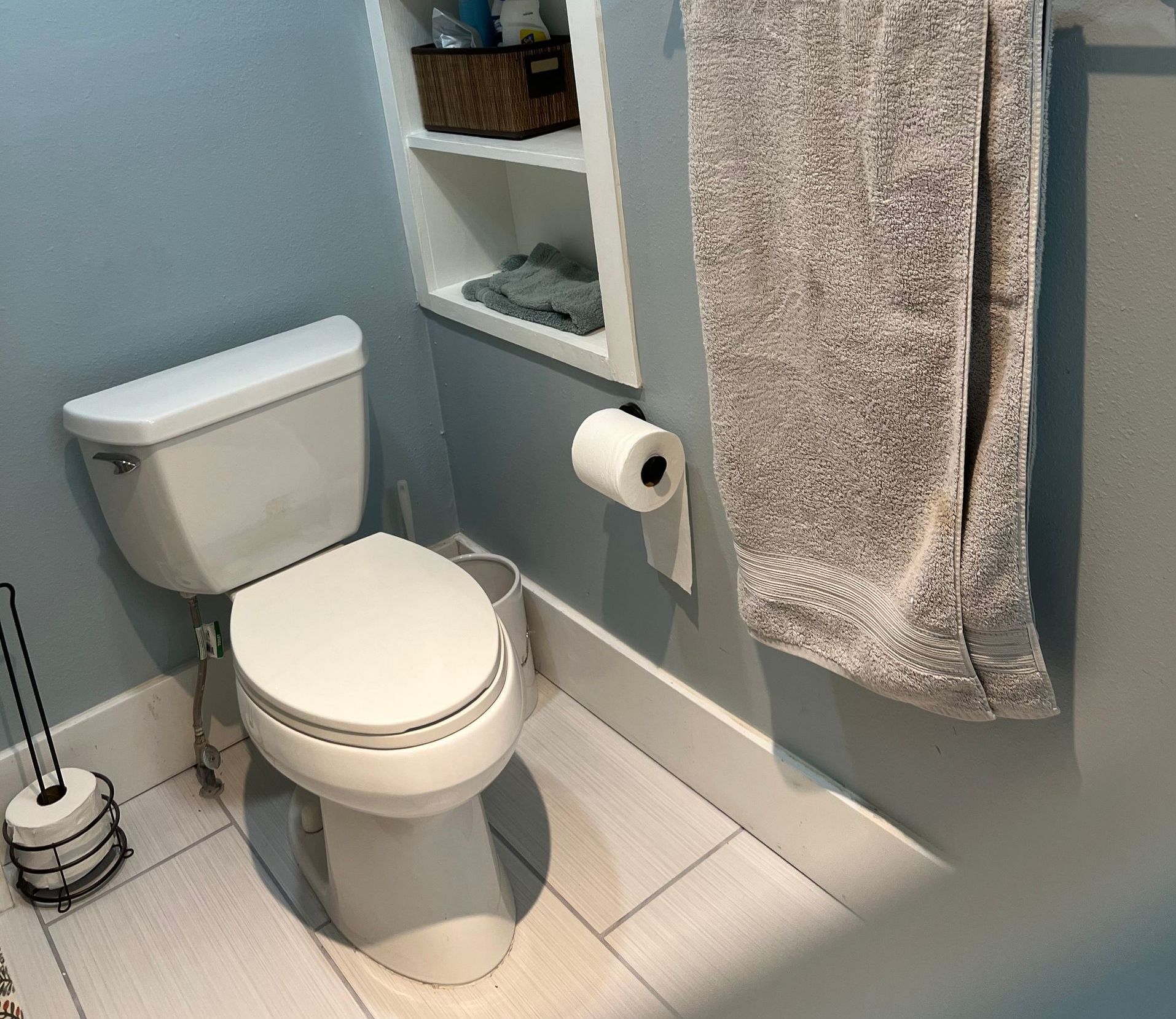 A bathroom with a toilet and a towel hanging on the wall