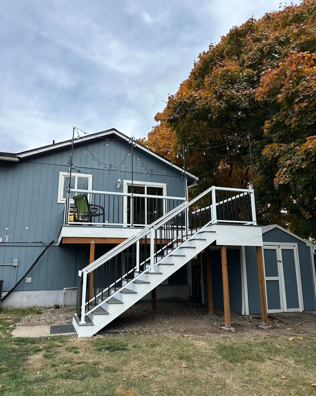 A blue house with stairs leading up to a deck