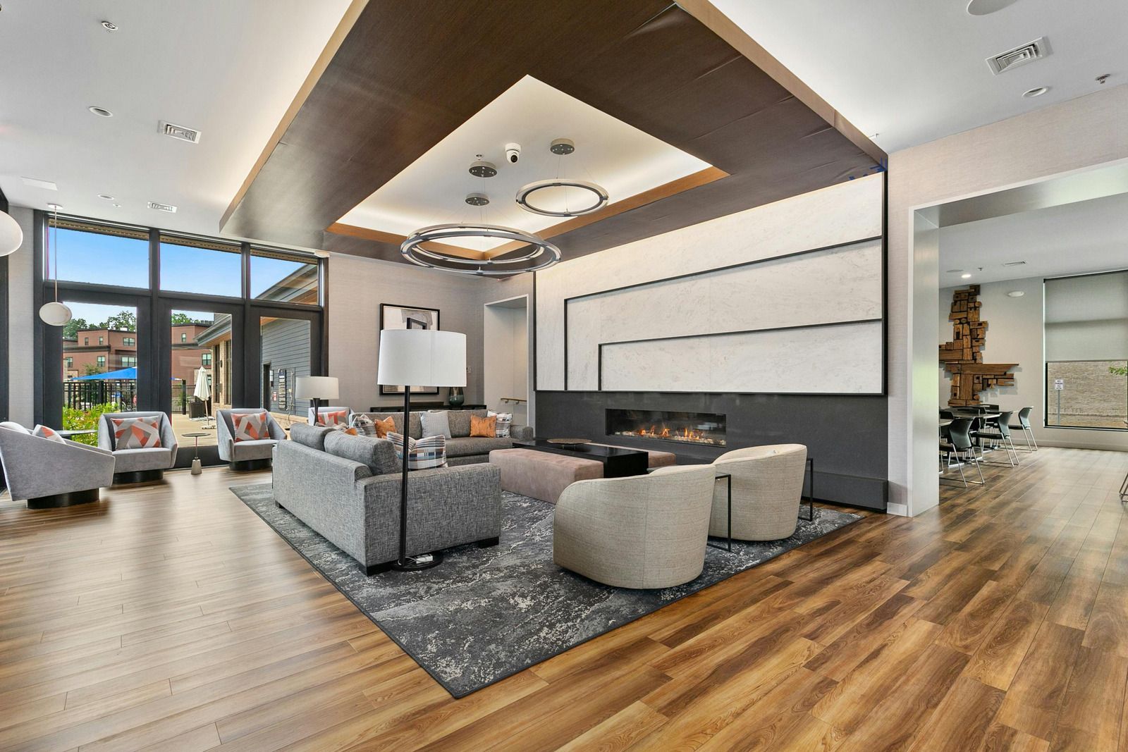 Modern open-concept living room with gray sofas, wood floors, and large windows.