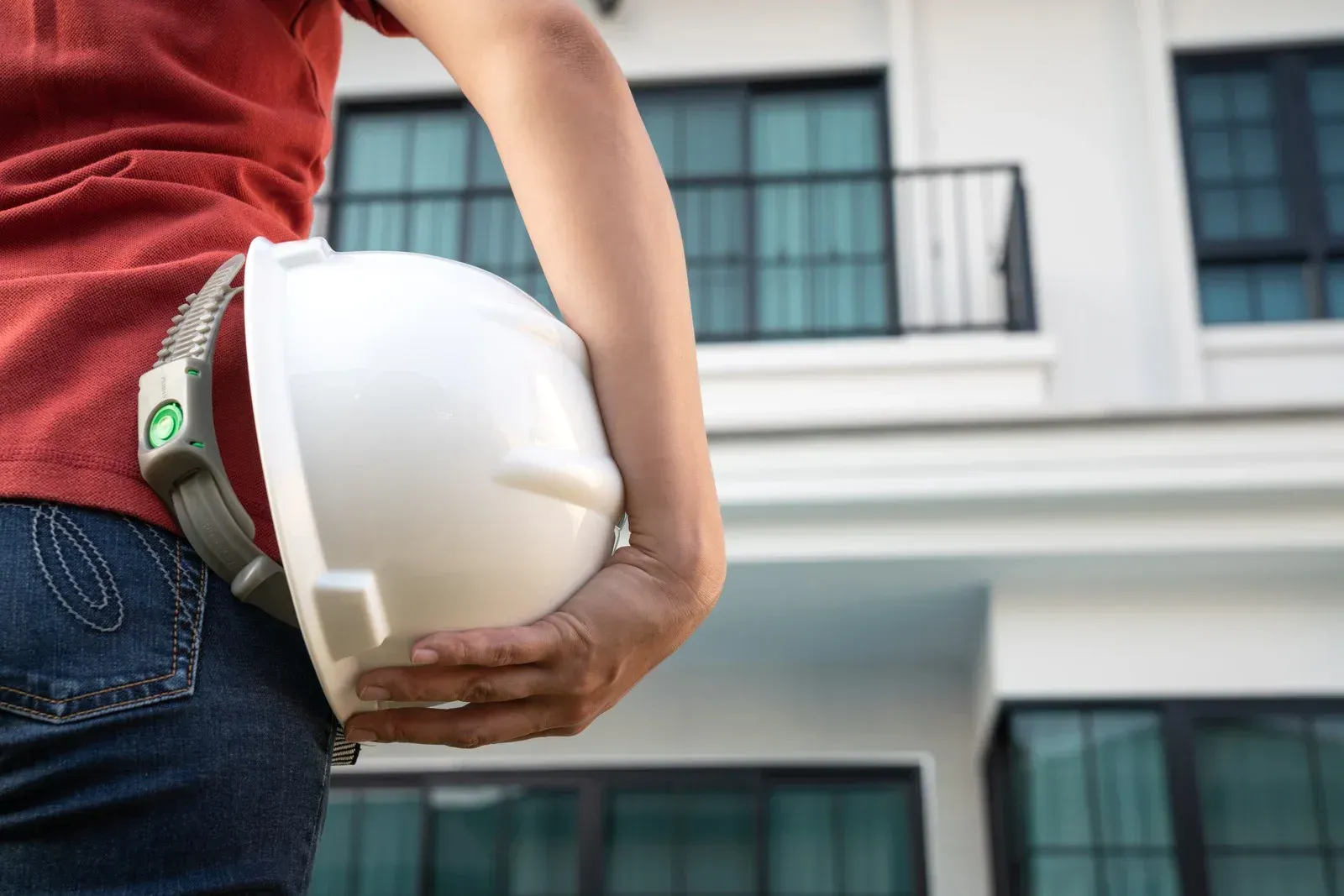 A woman is holding a hard hat in front of a building.