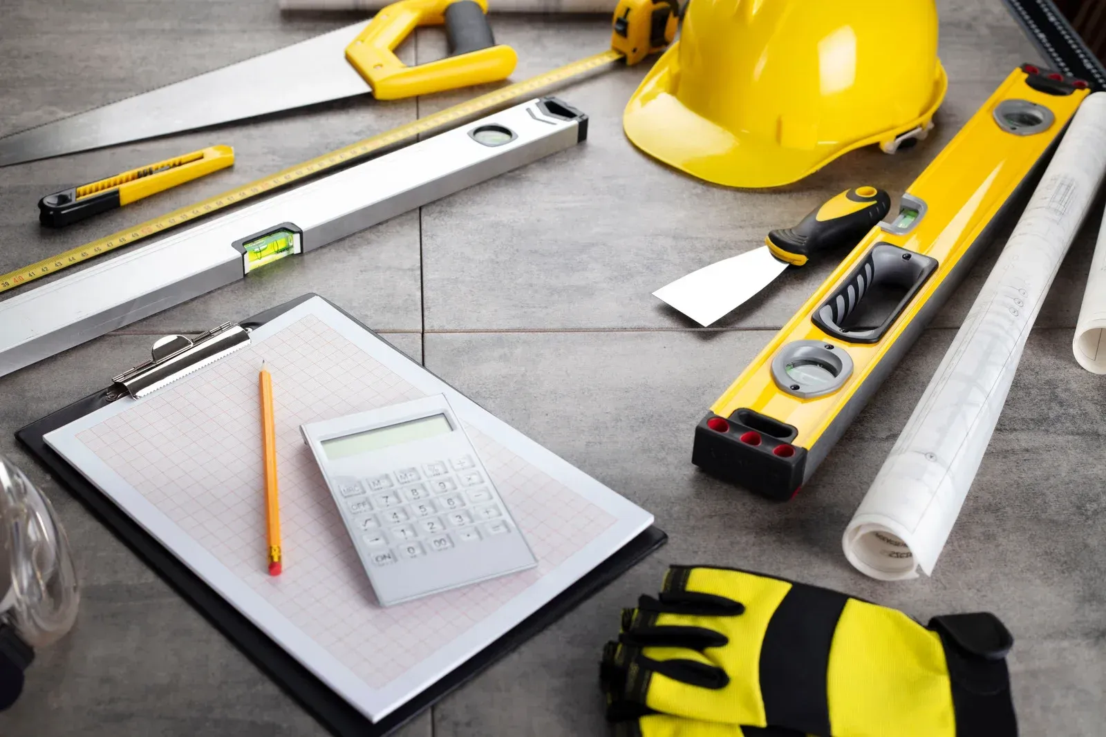 A clipboard with a calculator on it is surrounded by construction tools.