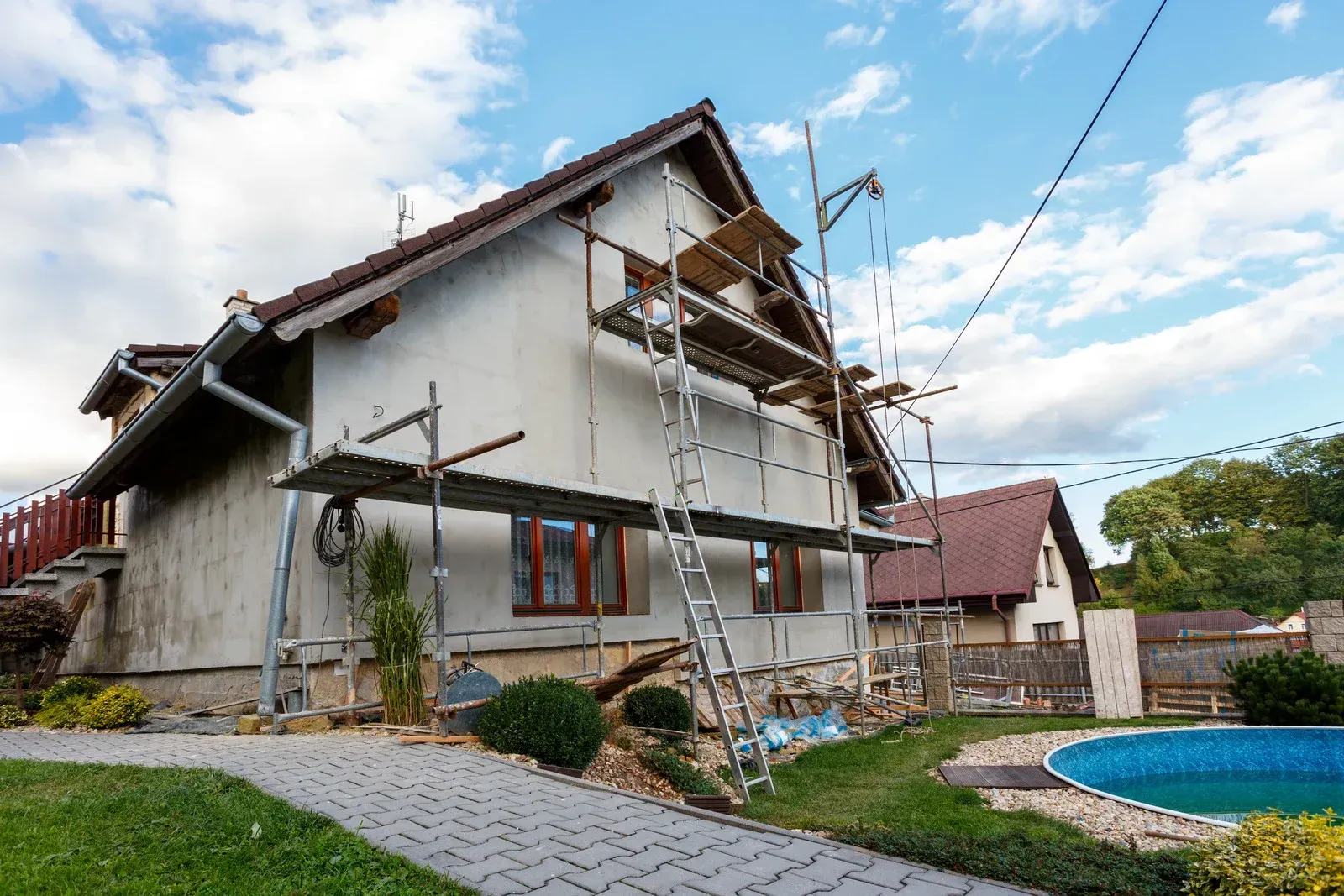 A house is being remodeled with scaffolding and a pool in the backyard.