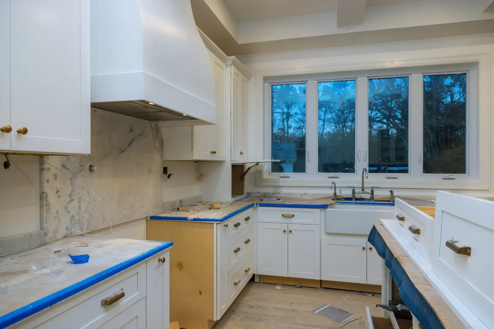 A kitchen under construction with white cabinets and a sink.