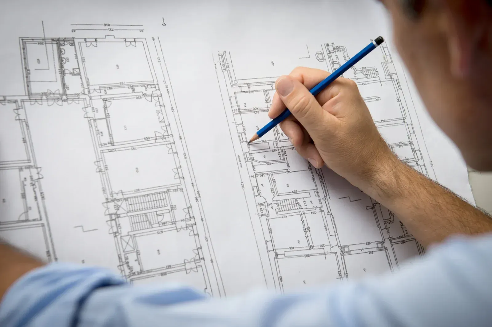 A man is drawing a floor plan with a pencil.