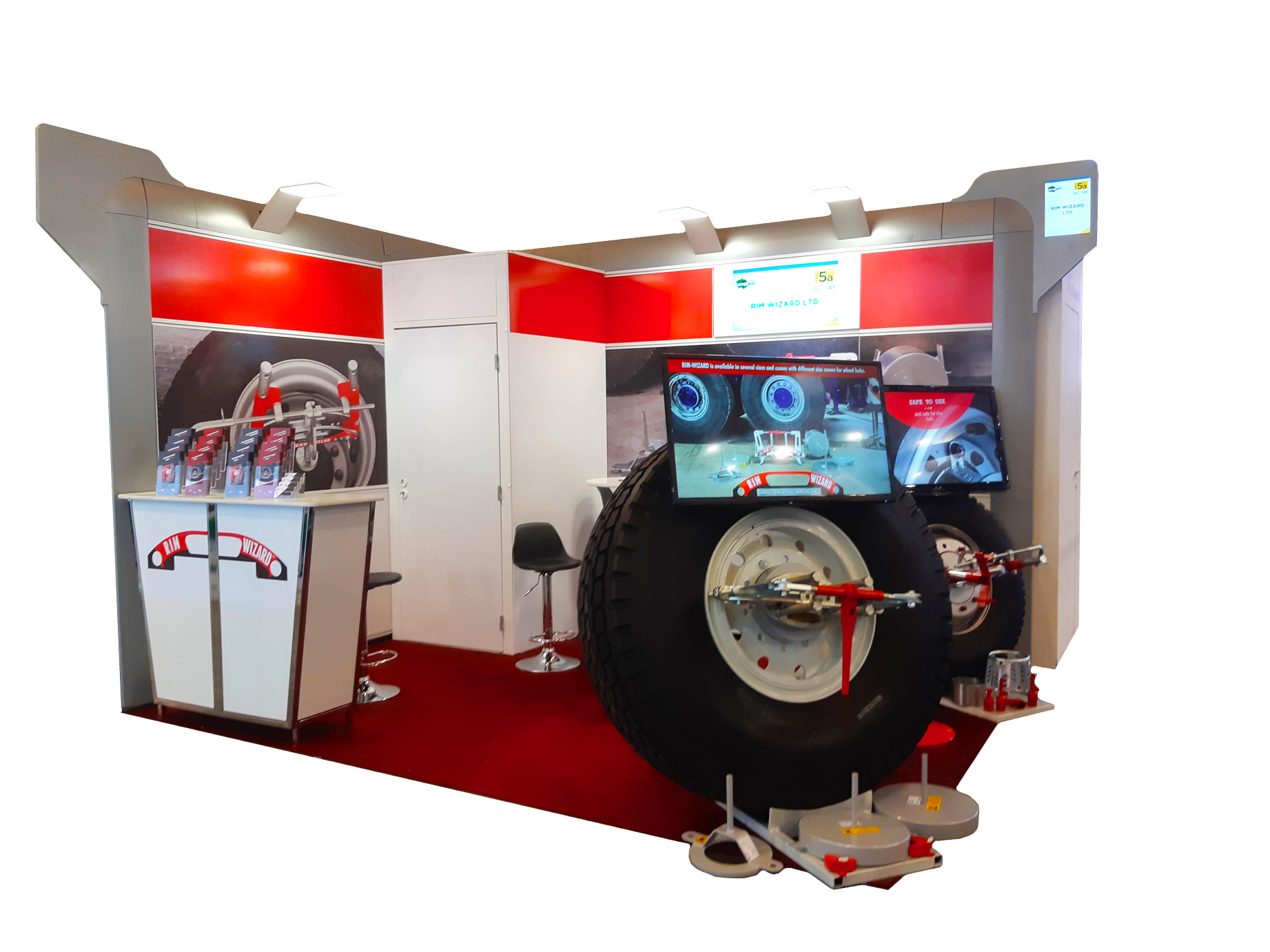 Näyttelyosasto, jossa on suuri renkaiden ulosvetolaite. Punainen ja valkoinen värimaailma, esillä monitorit.