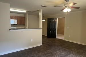 An empty living room with hardwood floors and a ceiling fan.