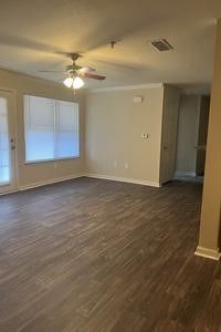 An empty living room with hardwood floors and a ceiling fan.