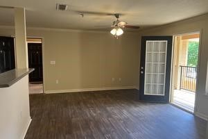 An empty living room with hardwood floors and a ceiling fan.