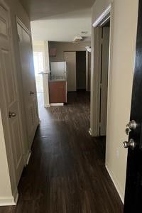 A hallway in a house with hardwood floors and a refrigerator.