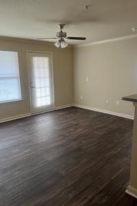 An empty living room with hardwood floors and a ceiling fan.