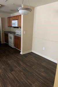 A kitchen with a stove , microwave , cabinets and hardwood floors.