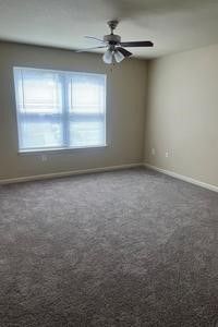 An empty bedroom with a ceiling fan and a window.