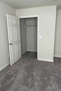An empty bedroom with a closet and a door open.