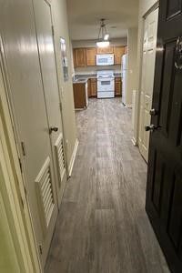 A hallway leading to a kitchen in a house.