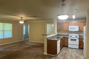 A kitchen with a stove , refrigerator , microwave and sink.