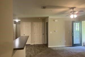 An empty living room with a ceiling fan and a sliding glass door.