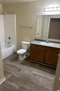 A bathroom with a toilet , sink , bathtub and mirror.