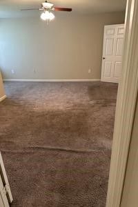 An empty room with a ceiling fan and a carpeted floor.
