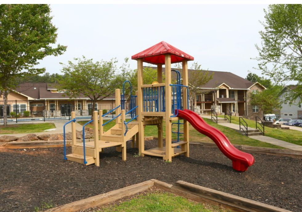A wooden playground with a red slide and stairs