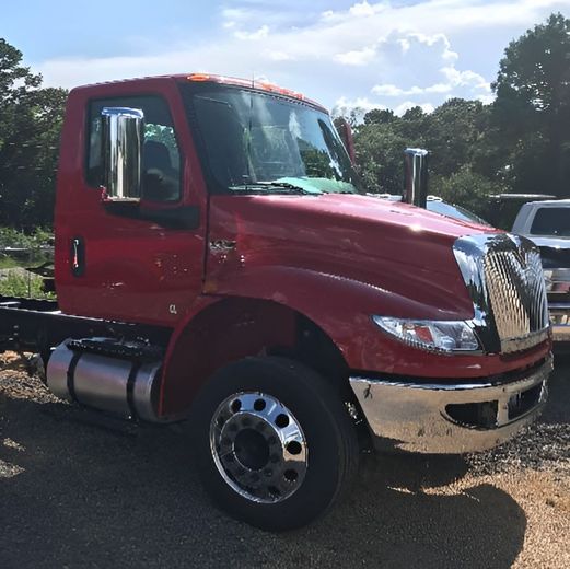 Red International truck cab on a sunny day, with chrome details and empty chassis.