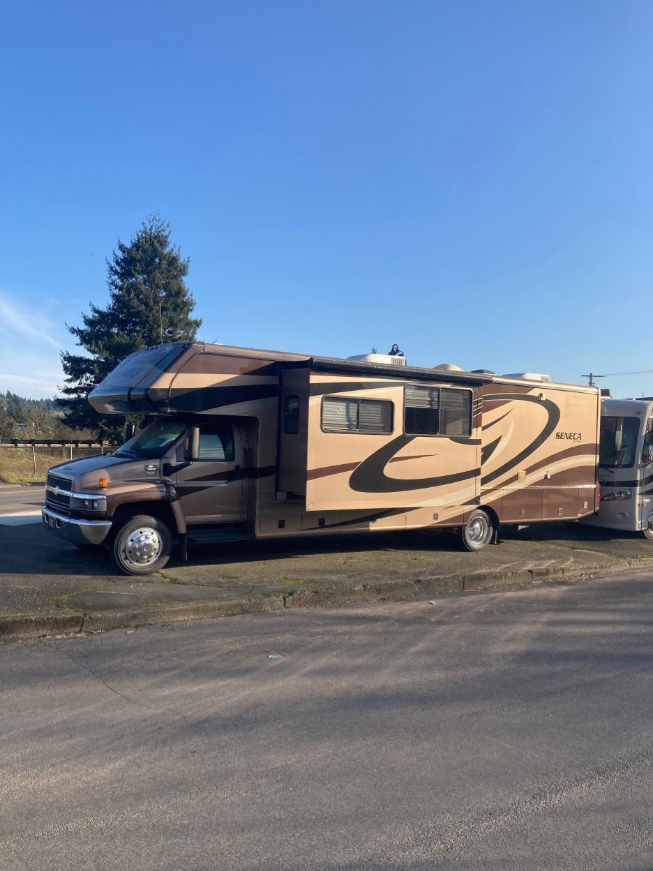 Brown and tan RV parked on asphalt with a blue sky background.