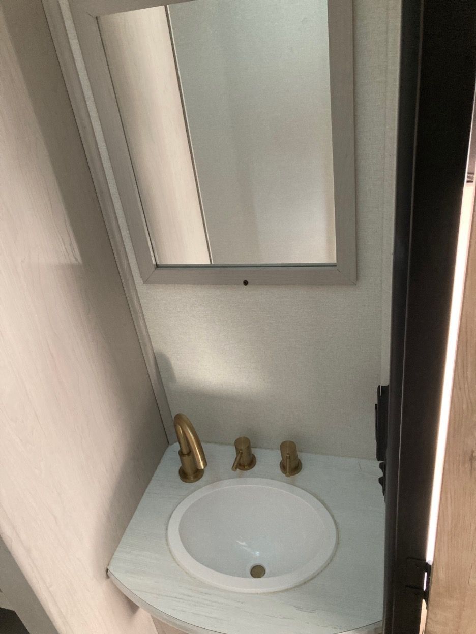 Small bathroom with a white sink, gold faucet, and a mirror.