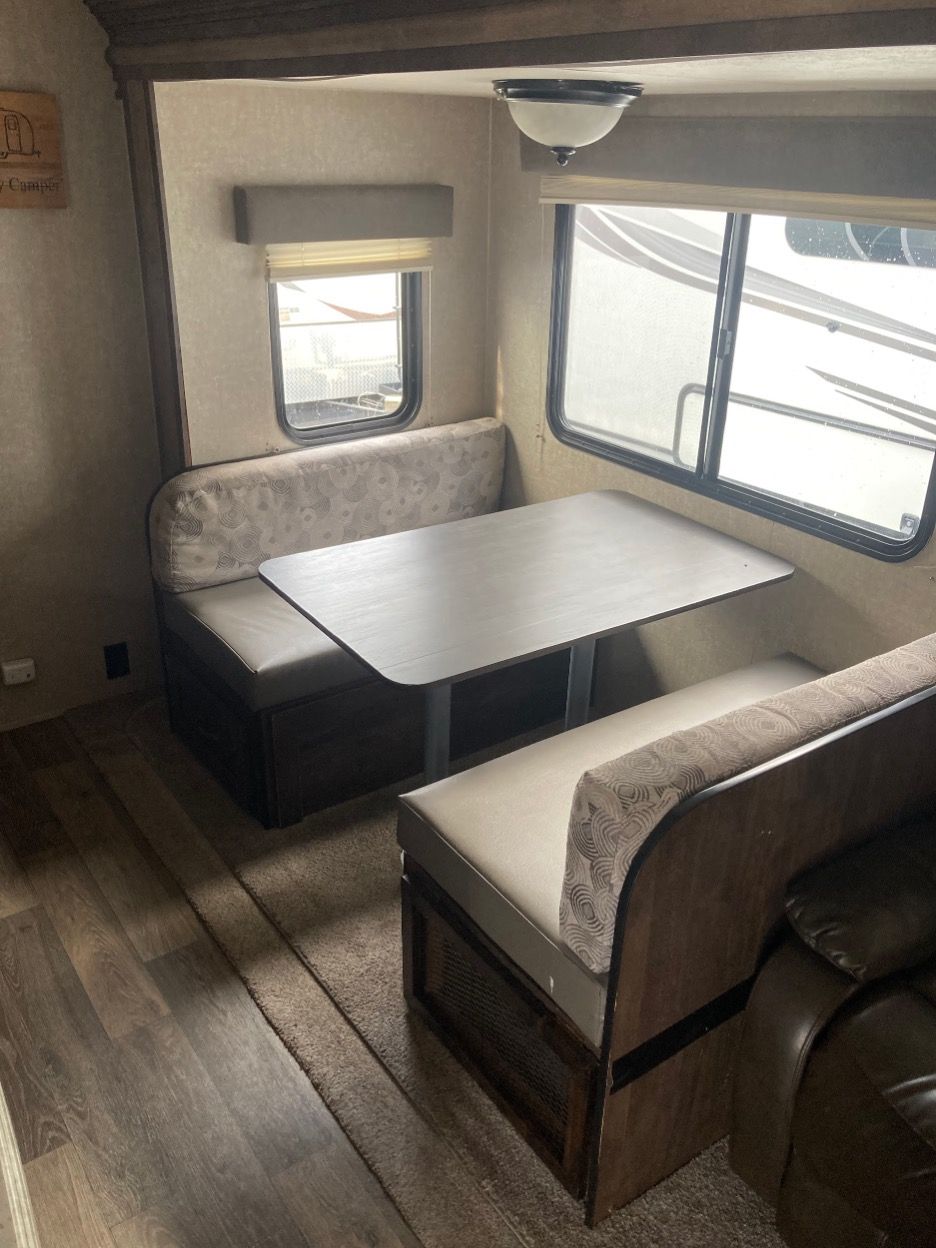 Interior of a camper with a booth dinette, table, and windows.