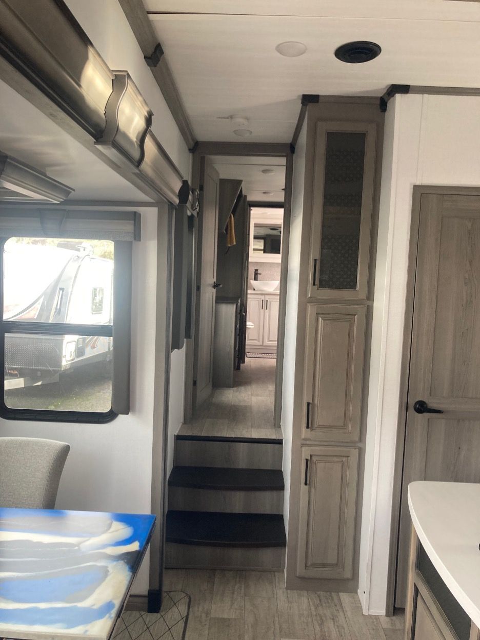 Interior of a recreational vehicle with steps leading to a hallway, cabinets, and a window.