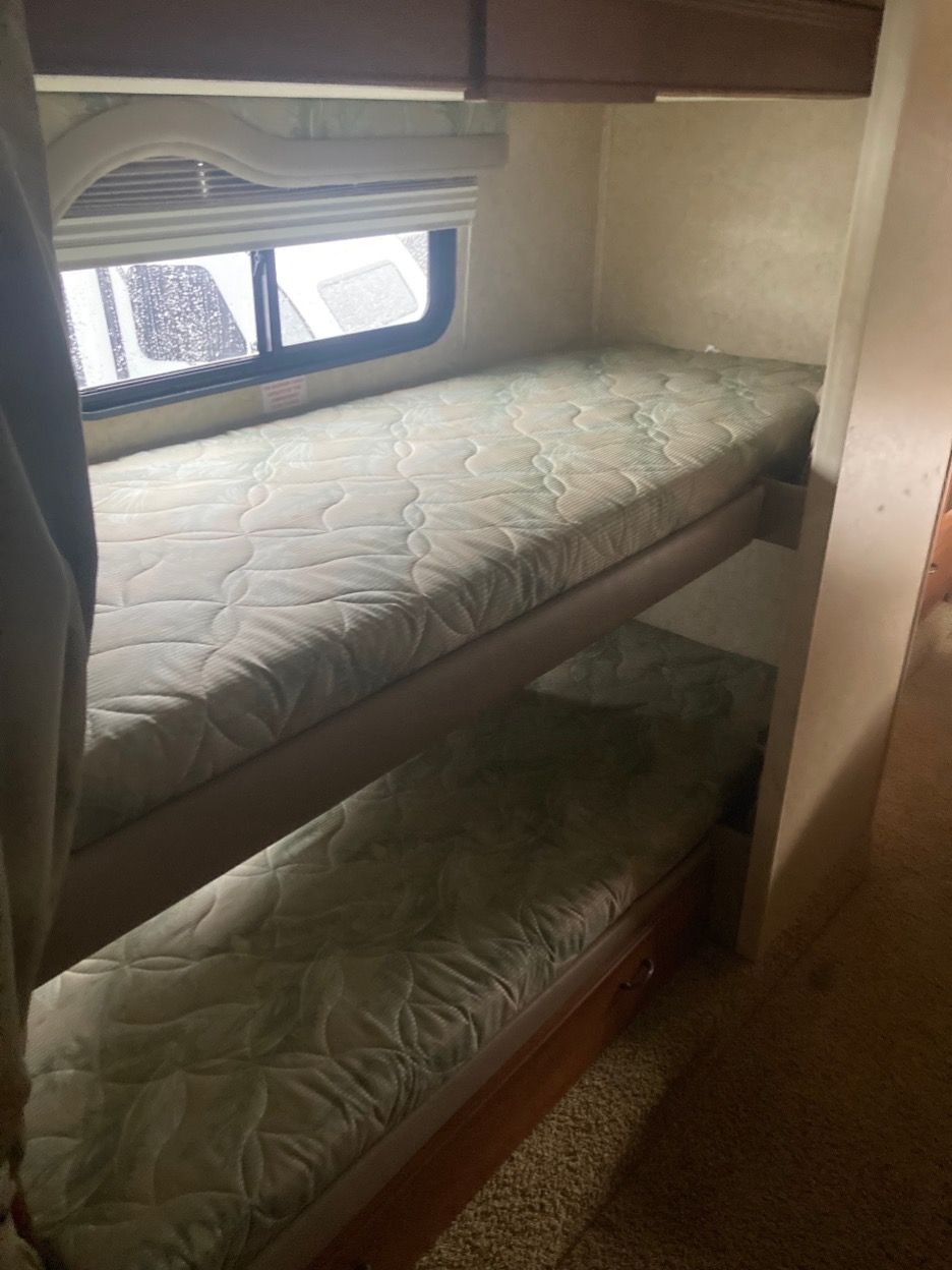 Bunk beds in a small room with a window. Both beds have patterned mattresses.