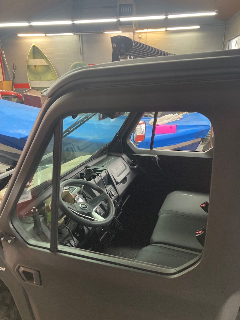 Side view of a dark gray vehicle's interior. Steering wheel, dashboard, and black seat are visible through the window.
