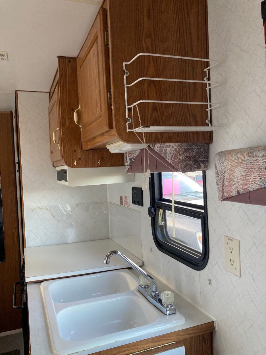 RV kitchen with a sink, cabinets, spice rack, and window.