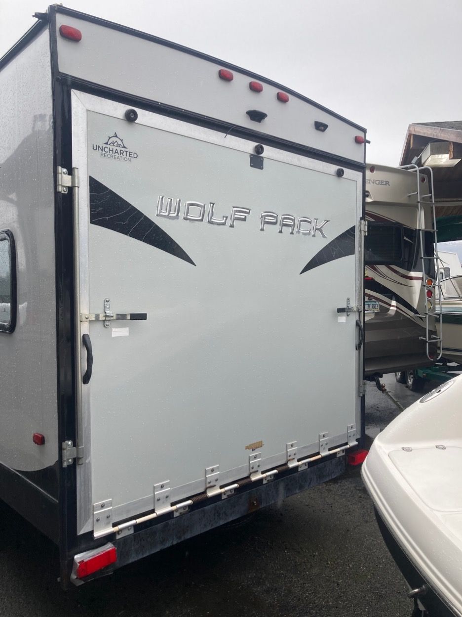 Rear view of a light gray Wolf Pack toy hauler with a ramp door.