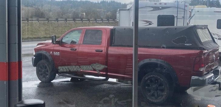 Red Dodge Ram truck with black accents and canopy. Parked outdoors on a cloudy day.