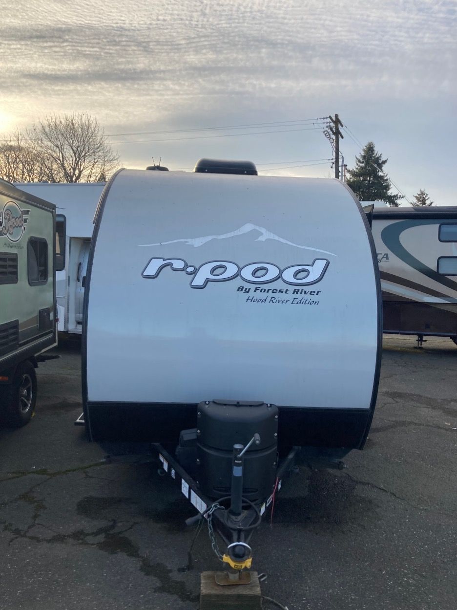 White r-pod travel trailer with black accents, parked outside. 