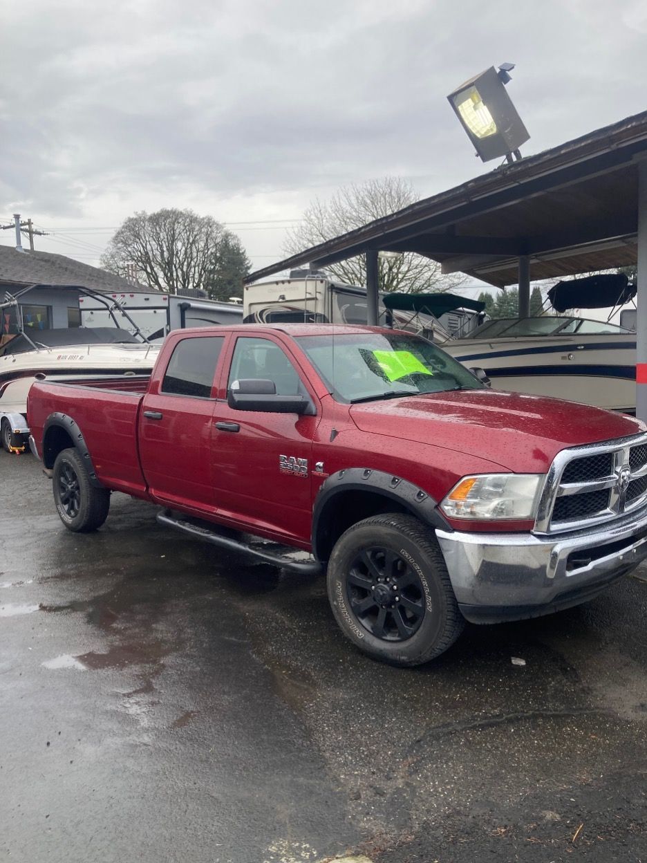 Red Ram pickup truck parked near boats at a dealership.