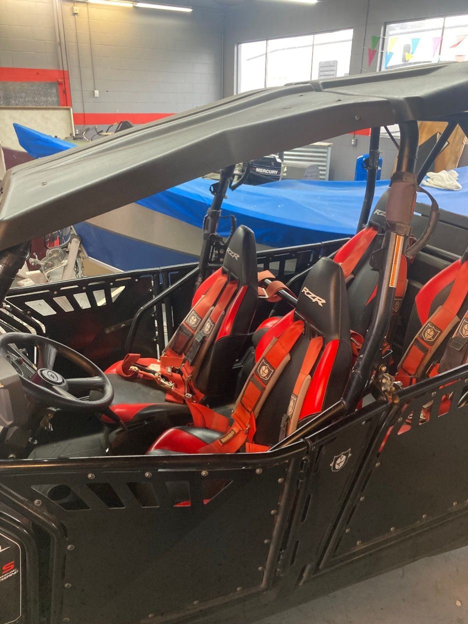 Black side-by-side UTV with red seats, roll cage, and canopy, parked inside a shop.