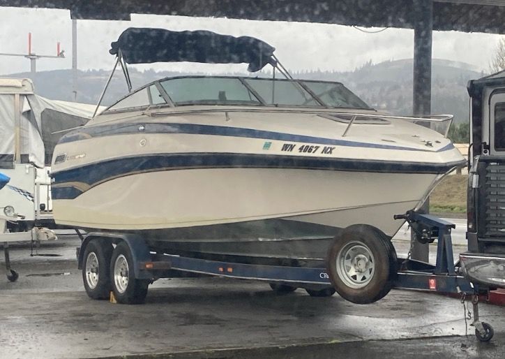 White and blue boat on a trailer, under a cloudy sky. Oregon license plate.
