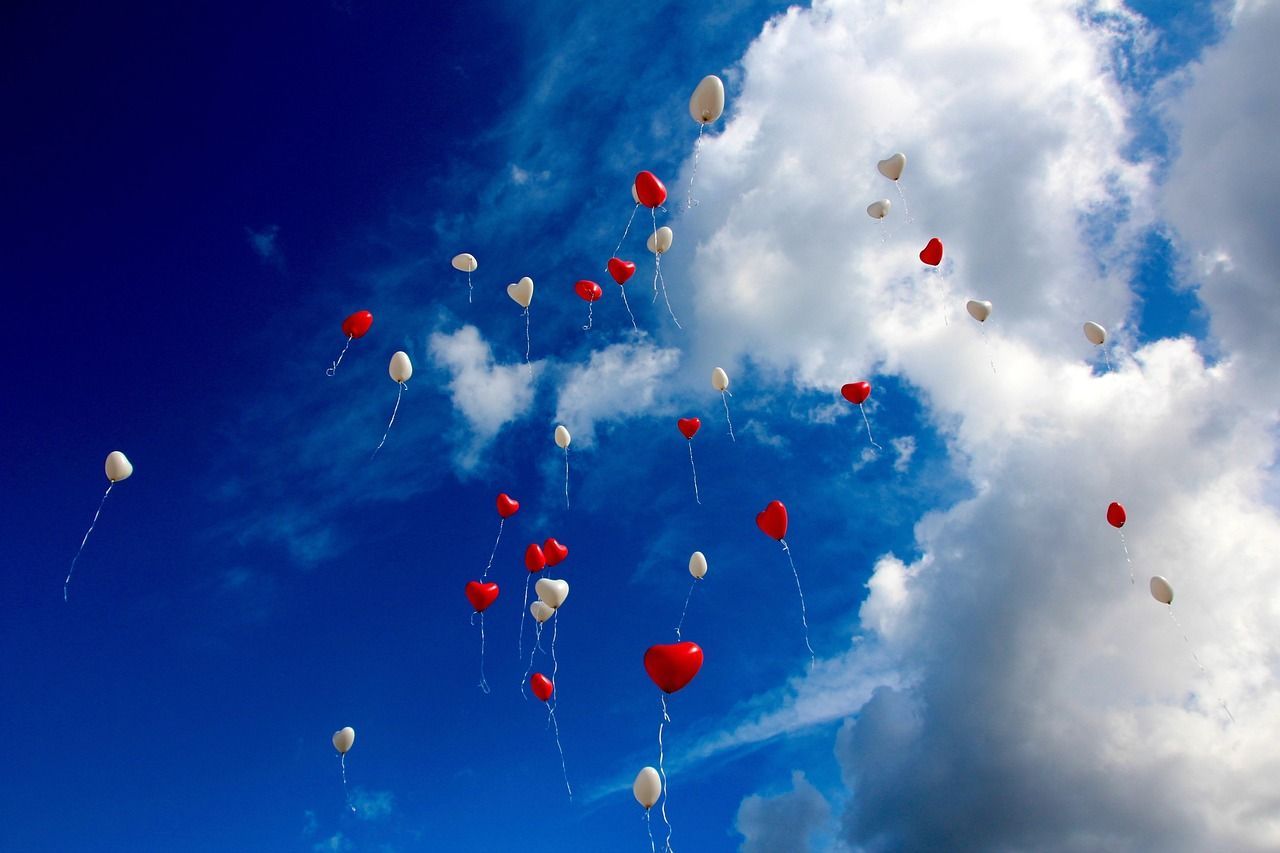 Red and white heart ballopns being released into the air