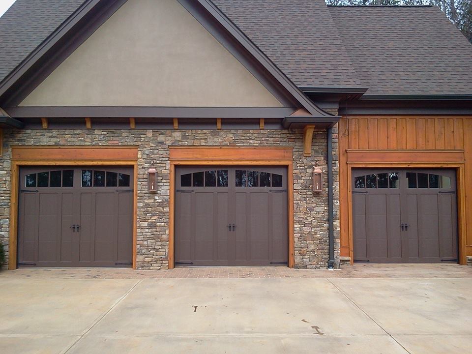 A house with three garage doors and a stone wall