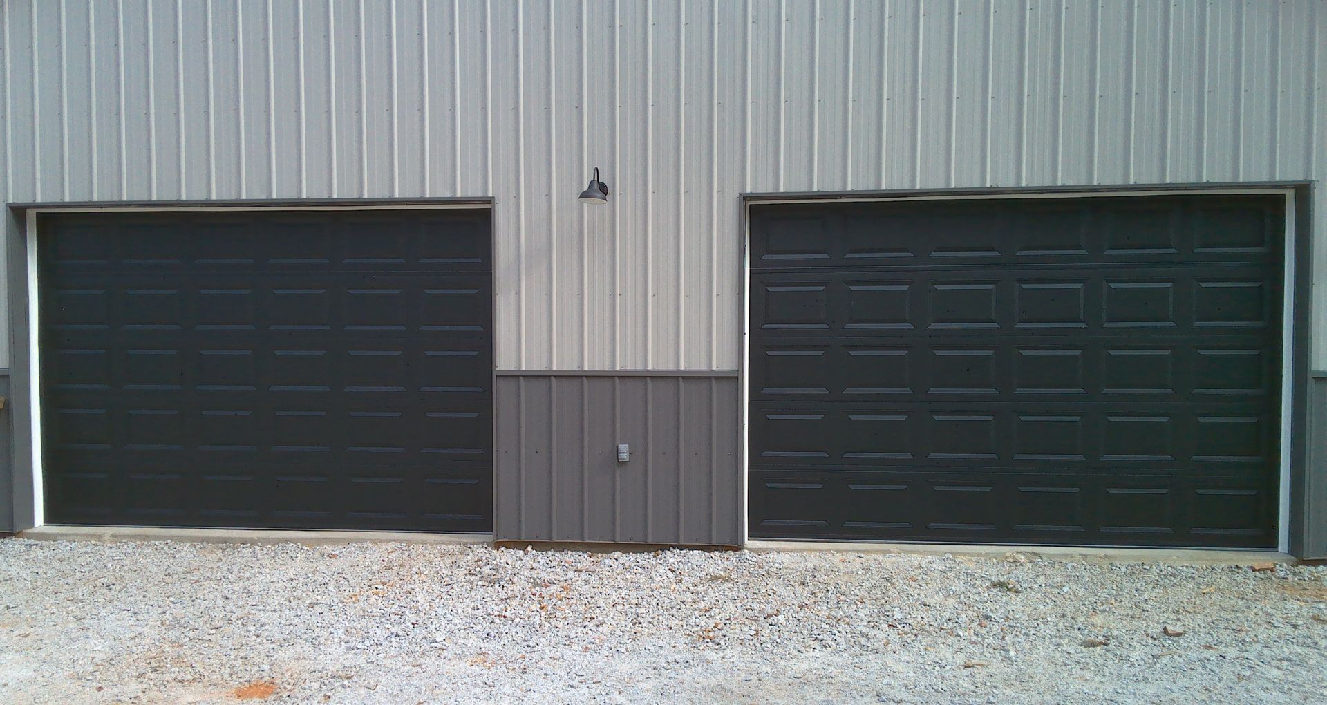 There are two garage doors on the side of a building.