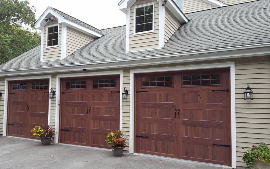 There are three garage doors on the side of a house.