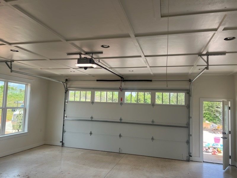 An empty garage with a garage door open and a ceiling fan.
