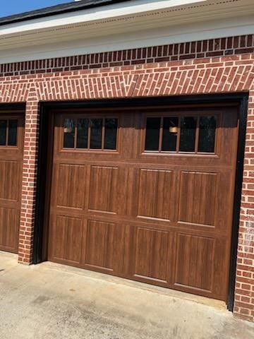 A pair of wooden garage doors on a brick building.