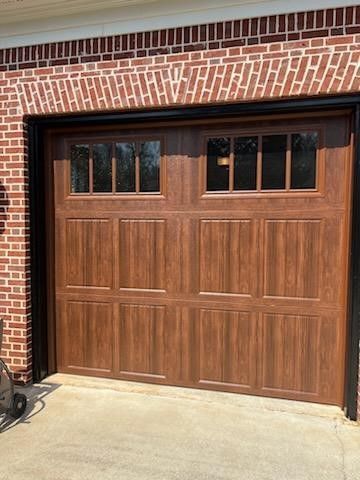 A wooden garage door is sitting in front of a brick building.