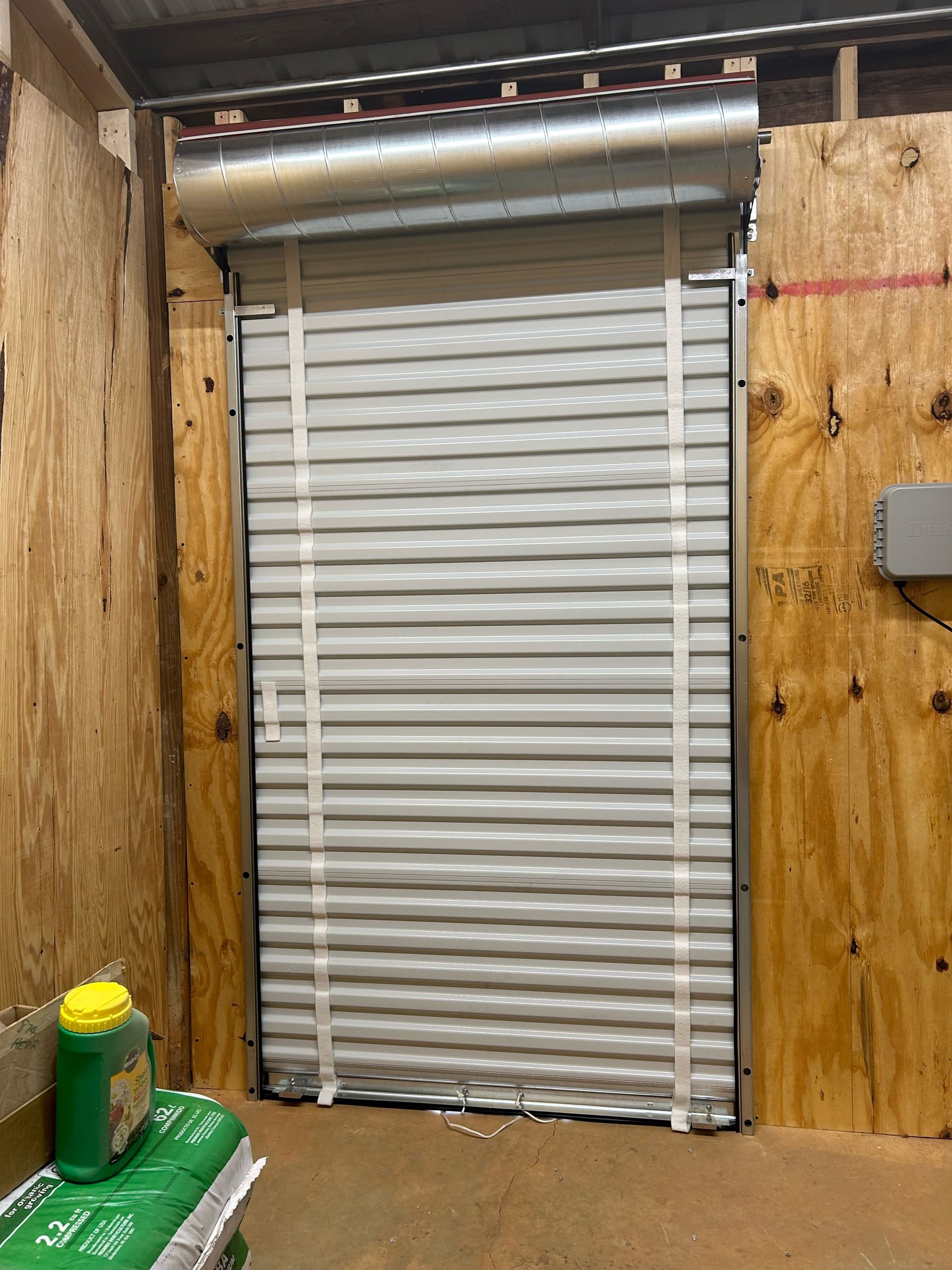 A garage door is open in a room with wooden walls.