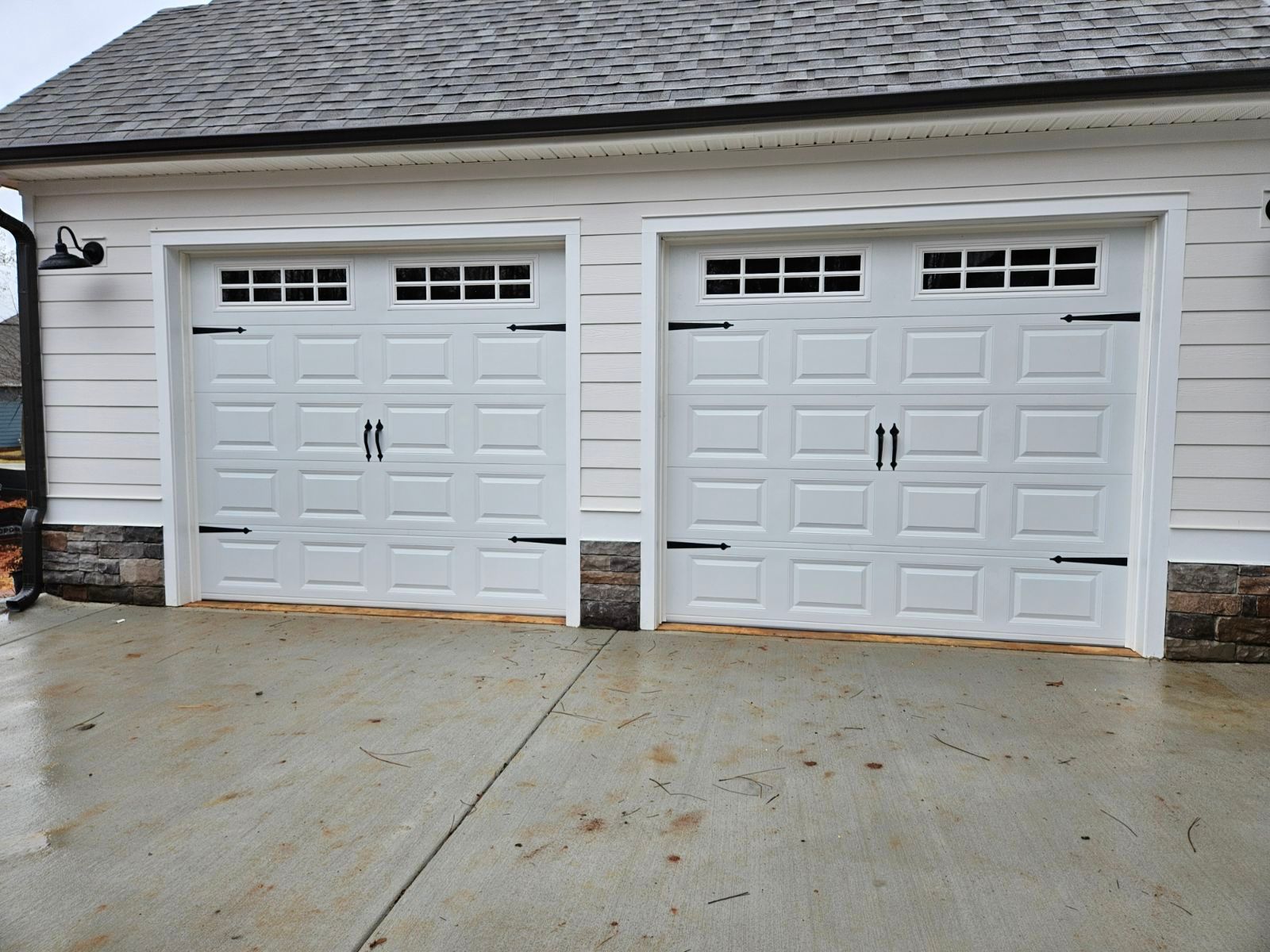 A white garage with two white garage doors and a gray roof