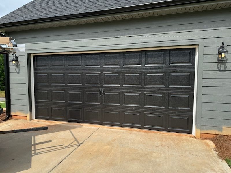 A black garage door is on the side of a house